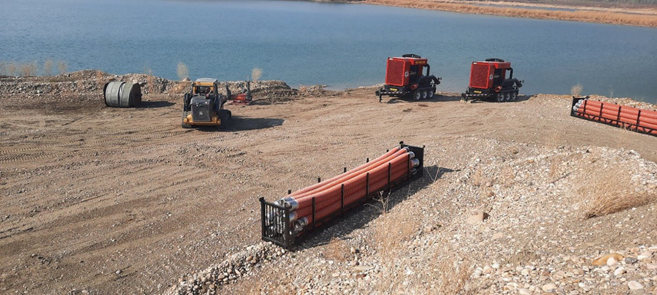 Construction equipment and large pipes beside water reservoir