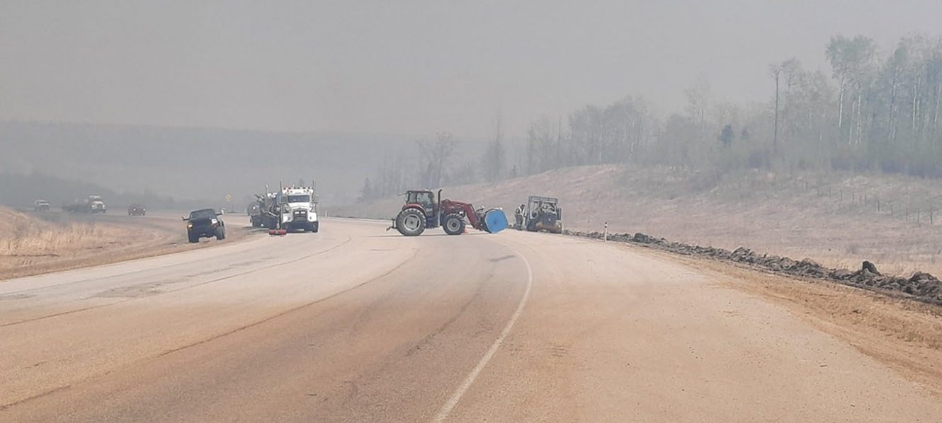 Tractor and trucks blocking smoky rural highway