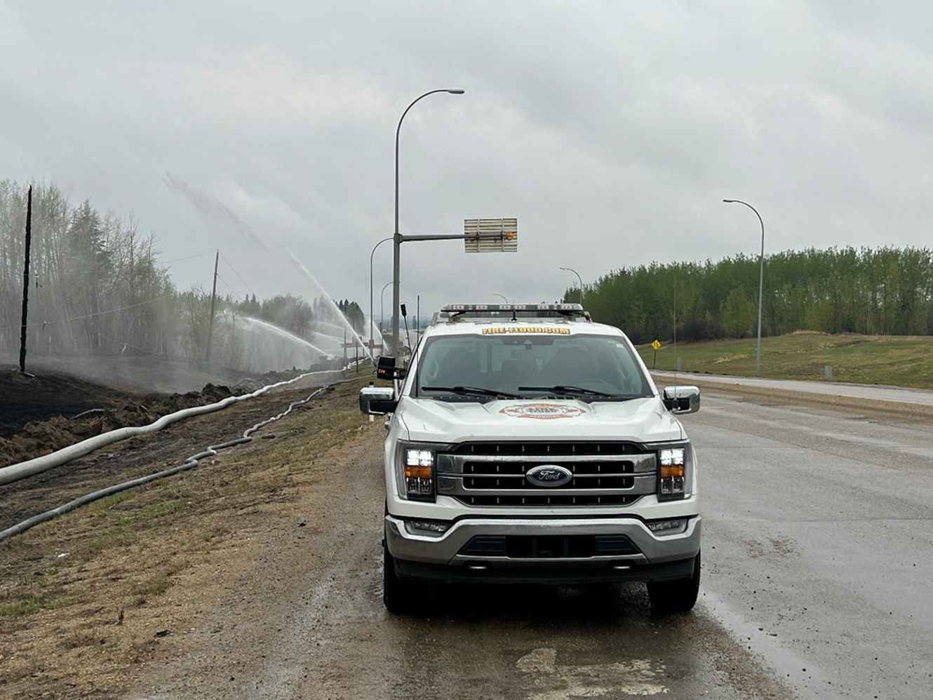 White pickup truck near roadside water spraying hoses