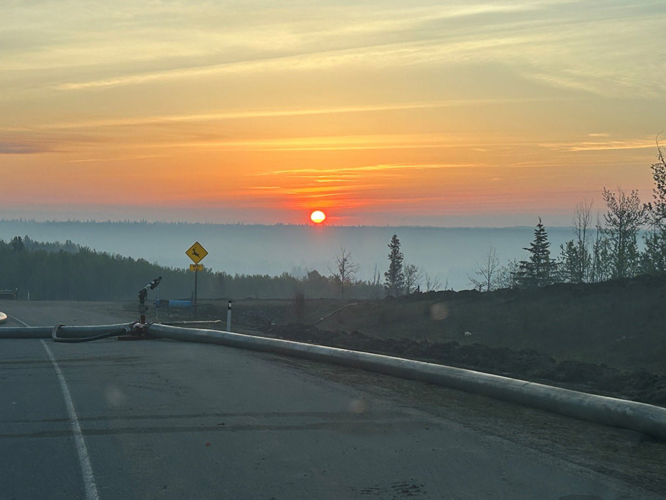 Sunrise over misty forest with road and pipe