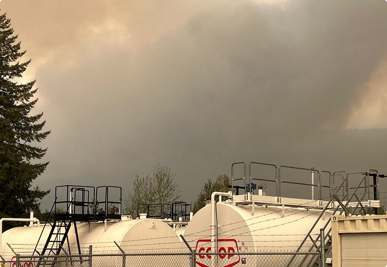 Industrial fuel storage tanks under smoky sky