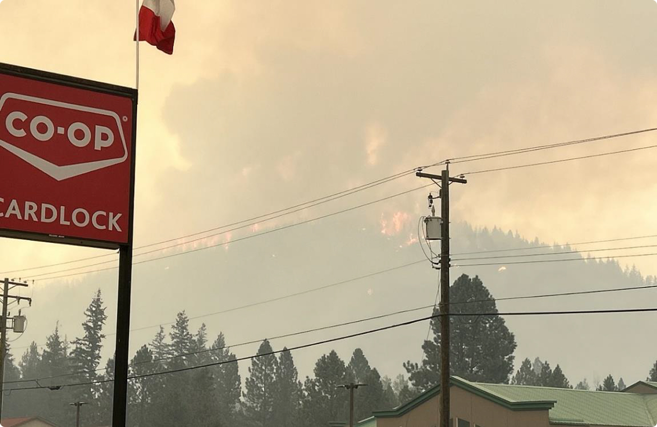 Wildfire burning forest behind CO-OP gas station sign
