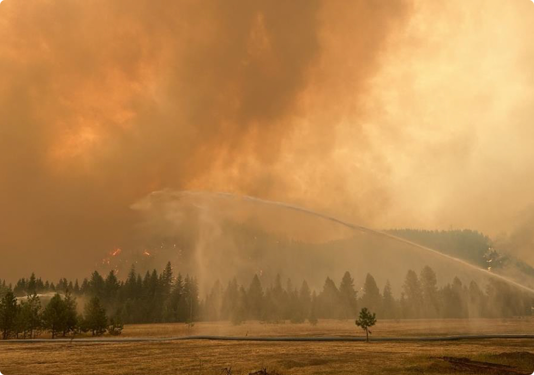 Wildfire smoke over forest with water spray