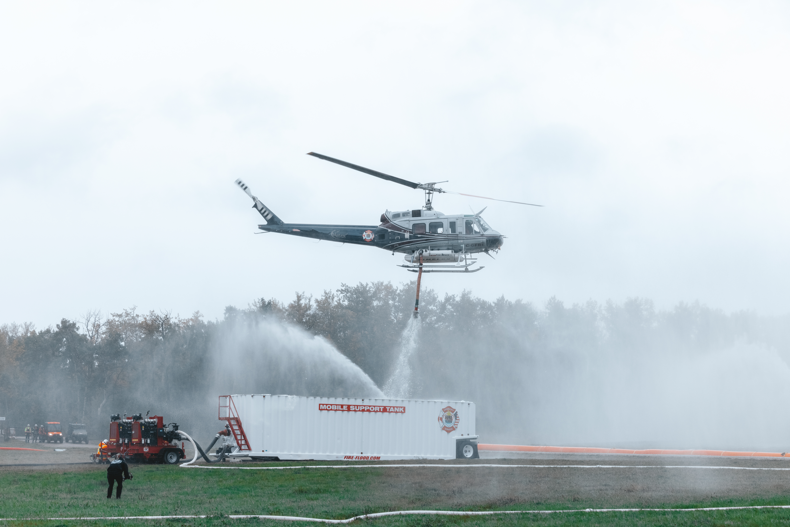 Helicopter dropping water into mobile support tank